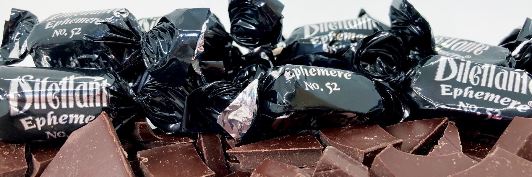 Dilettante Chocolates Dark Chocolate Ephemere Truffles laying on a bed of dark chocolate pieces