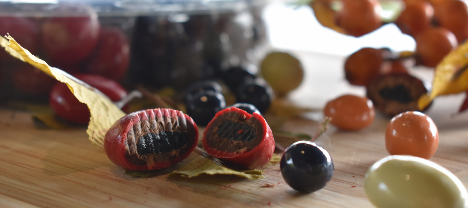 Dilettante Chocolates Chocolate-Covered Royal Cherry cut in half on a cutting board, revealing rich chocolate covering a dried royal cherry center.