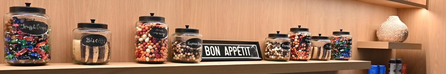 Dilettante Chocolates Bon Appetite sign beside other jars of TruffleCremes, Biscotti, and Chocolate-Covered Fruit